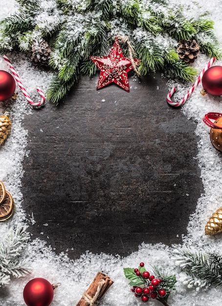 Kerstster vuren takken ballen jingle bells en decoraties op sneeuw. Vrije ruimte voor tekst.