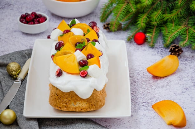 Kersttaart met marshmallowsuikerglazuur, veenbessen, kaki en gekarameliseerde mandarijnen bovenop