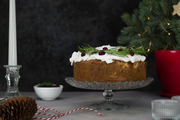 Kersttaart met rozemarijn en rode bessen op een standaard op een grijze en zwarte achtergrond