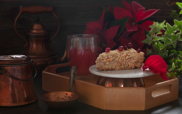 Kersttaart met veenbessen op tafel met bronzen keukengerei, kerststerbloem en cranberrydrank