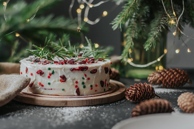 Foto kersttaart met witte kaascrème, versierd met veenbessen en rozemarijn.