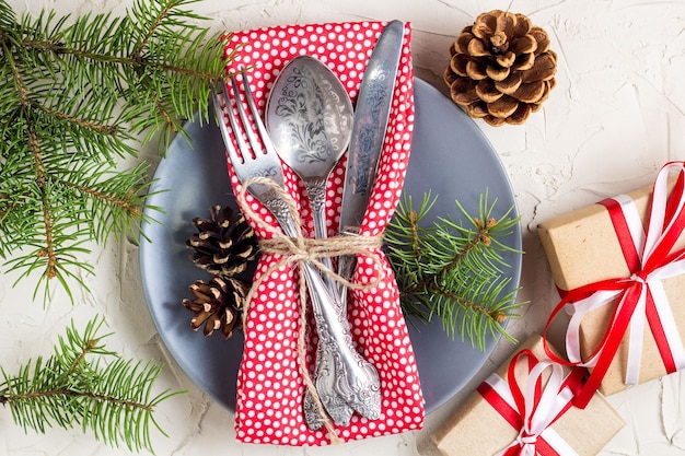 Kersttafel instelling met zuurstok, kerstboom, dennenappels en cadeau, op witte tafel, bovenaanzicht kopie ruimte.