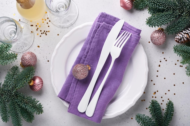 Kersttafel instelling witte kleur met zilverwerk, servet trendy kleur zeer peri in 2022 jaar, kerstballen, sterren, champagne, glazen op witte achtergrond voor xmas groeten. Bespotten.