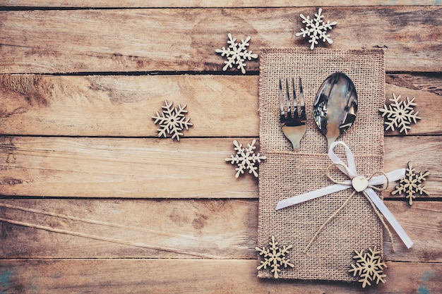 Kersttafel plaats instelling en zilverwerk, sneeuwvlokken op houten achtergrond met ruimte.