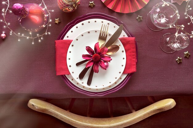 Kersttafelopstelling met borden, keukengerei, donkerrode en vergulde decoraties