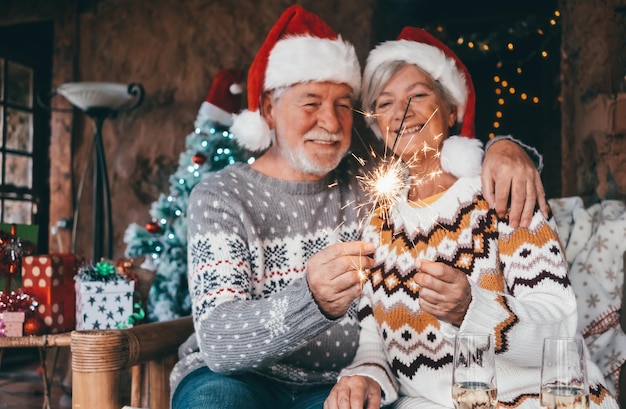 Kersttijd Portret van een vervaagd glimlachend oudere echtpaar in een kerstmanhoed met vonkellichten