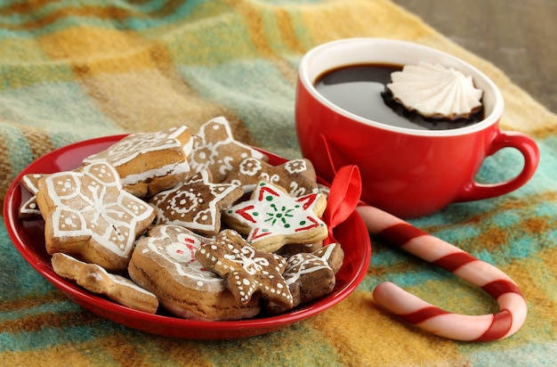 Kersttraktaties op bord en kopje koffie op geruite close-up