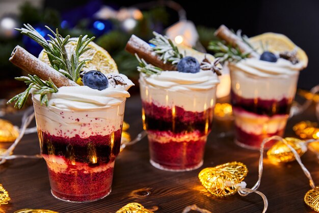 Kersttrifles in kopjes als dessert gedecoreerd met verse bosbessen en een vanillestokje