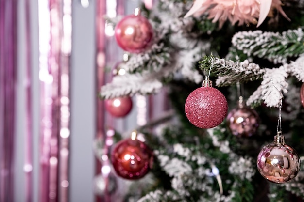 Kerstvakantie dennentakken conifer kegels zilverroze ornamentenVerfraaide kerstboomGlinsterende bal voor het nieuwe jaarKerstboom versierd met speelgoedlinten en lichten gloeiende slinger