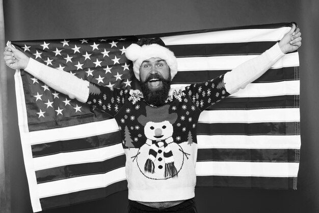 Foto kerstvakantie kerel viert kerst vrolijke hipster houd van je land kerstmis in de verenigde staten van amerika groeten aan al mijn landgenoten amerikaanse man houdt amerikaanse vlag nationale geest