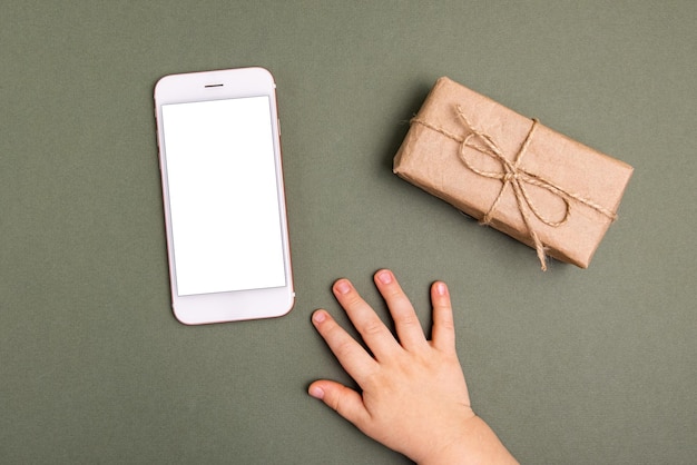 Kerstvakantie technologie achtergrond mobiele telefoon in handen van kinderen en geschenkdozen verpakt ambachtelijke papier...
