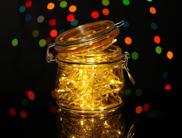 Kerstverlichting in glazen fles op de achtergrond van wazige lichten