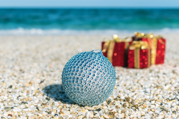 Kerstversiering en bal op het zand van een strand
