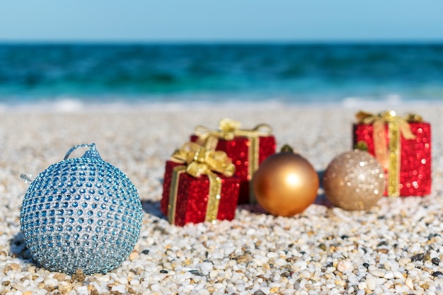 Kerstversiering en bal op het zand van een strand