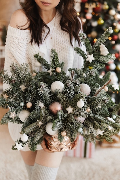 Kerstversiering in handen van de jonge schoonheid in een wollen trui