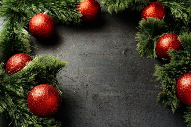 Kerstversiering met fir tree takken en rode kerstballen op zwart