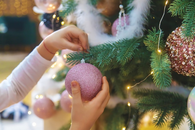 Kerstversiering op de boom in de handen van een kind. Selectieve aandacht. Vakantie.