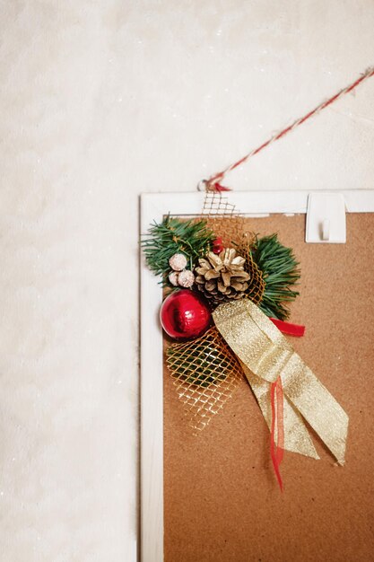 Kerstversiering van dennentakken, ballen en linten die op een thuisspatbord hangen op een witte achtergrond