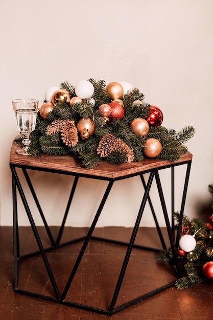 Kerstversieringen gemaakt van dennen en kegels op een houten tafel bij een witte muur