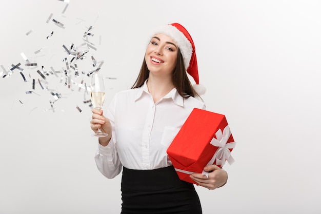 Kerstviering Jonge mooie zakenvrouw die Kerstmis viert met een glas champagne en confetti achtergrond