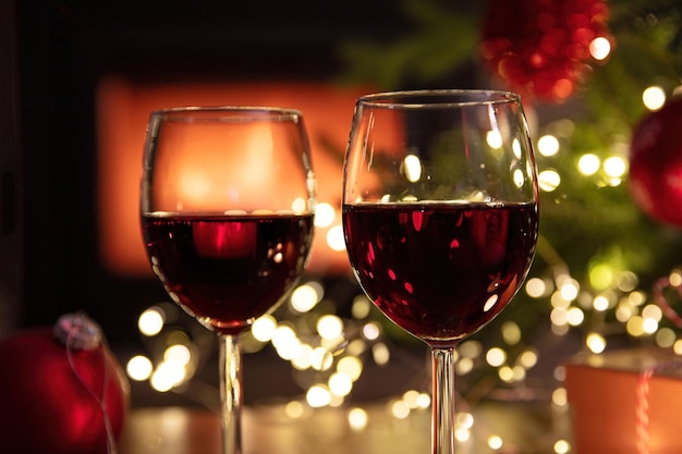 Kerstviering Rode wijnglazen Xmas presenteert en decoratie op tafel open haard achtergrond Xmas viering