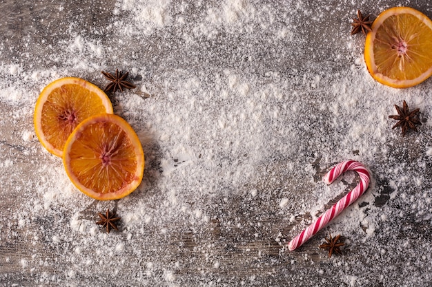 Kerstvoedselachtergrond met sinaasappelen, steranijs, en bloem