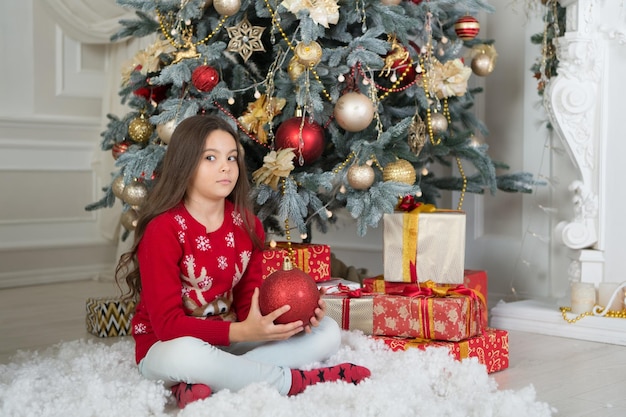 Kerstvoorbereiding Klein meisje versier kerstboom Klein kind viert kerstmis en nieuwjaar Vrolijk kerstfeest Gelukkig nieuwjaar