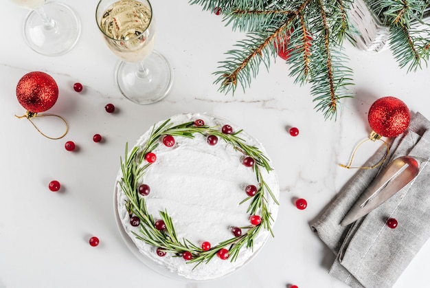 Kerstvruchtentaart of -pudding, versierd met rozemarijn en cranberry, met kerstdecoratie, op witte marmeren tafel, kopie ruimte