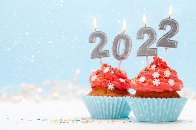 Kerstwenskaart met cupcakes en nieuwjaarskaarsen voor 2022