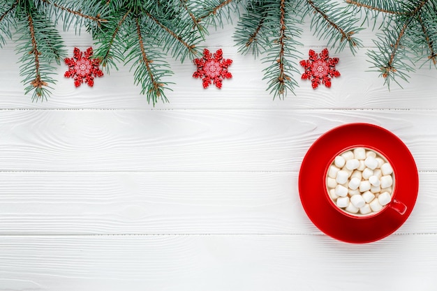 Kerstwenskaart met rode kop koffie en sneeuwvlokken. Nieuwjaar frame met feestelijke decoraties. Vuren takken. Sjabloon met kopie ruimte. Patroon met plaats voor tekst. Wintermodel.