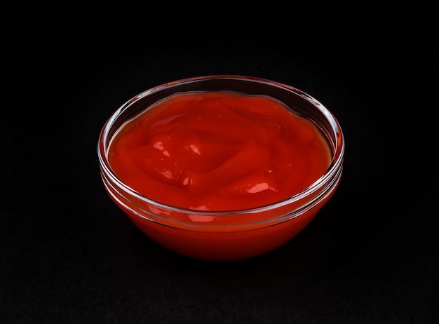 Ketchup in bowl on black