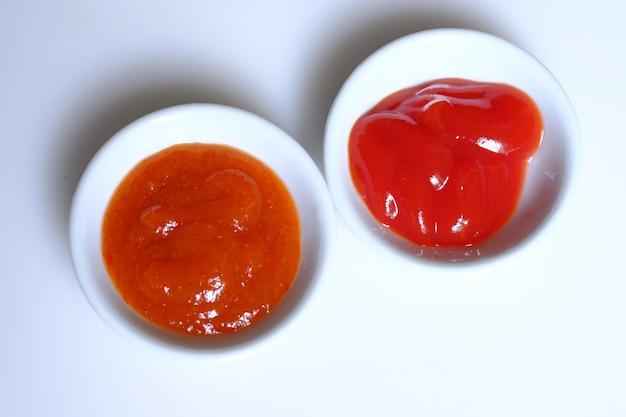 ketchup en chilisaus in een witte keramische kom. voedingssupplement. saus tomaat. sambal.