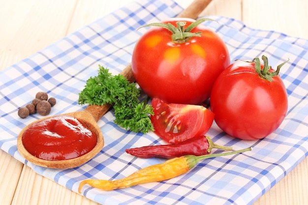 Ketchup en rijpe tomaten op houten tafel