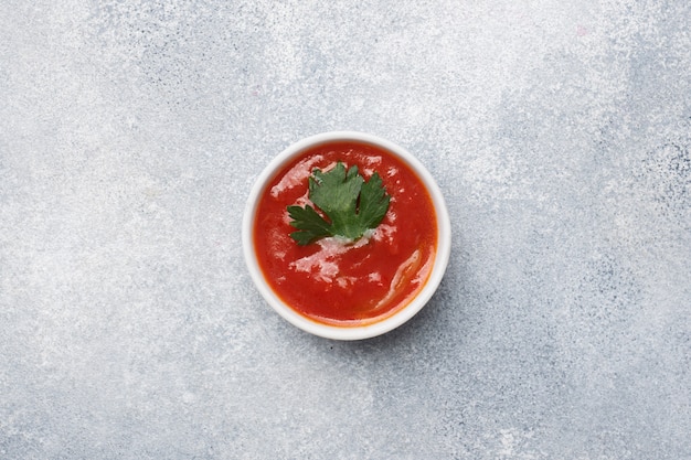 Ketchup greens in plates on a gray concrete table with copy space.