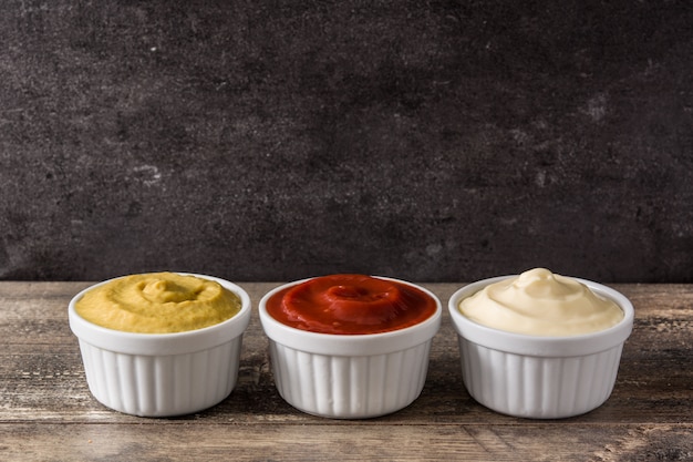 Ketchup,mustard and mayonnaise in a bowls on wooden table