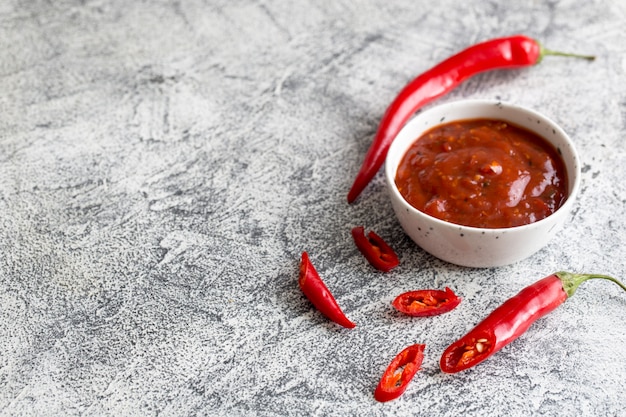 Photo ketchup with hot chili pepper and garlic on a gray concrete background