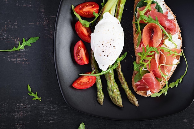 Colazione keto asparagi fritti con uovo in camicia e pane tostato con prosciutto o jamon dieta chetogenica cibo sano vista dall'alto piatto