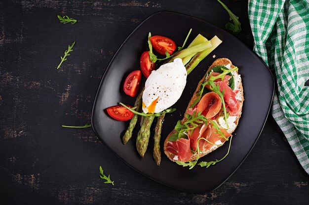 Keto breakfast Fried asparagus with poached egg and toast with prosciutto or jamon Ketogenic diet Healthy food Top view flat lay