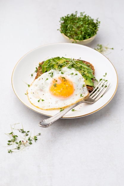 Keto breakfast fried egg avocado and bread in a white plate Keto diet concept