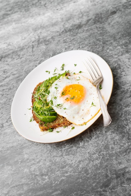 Keto breakfast fried egg avocado and bread in a white plate Keto diet concept