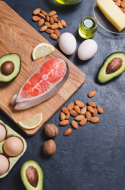 Photo keto diet, low carb healthy food. avocado, fish, oil, nuts on black background