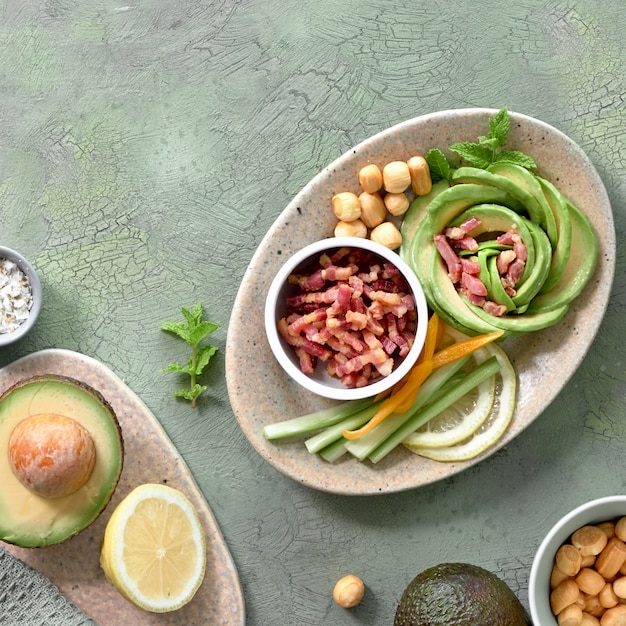 Keto diet, top view of avocado rose salad with bacon cubes and smoked cheese on green table