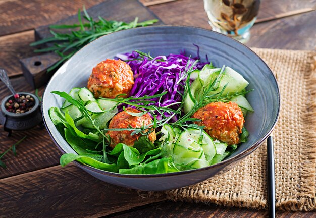 Keto / ketogeen voedsel. Kippengehaktballetjes en salade op houten lijst. Avondeten. Boeddha schaal.