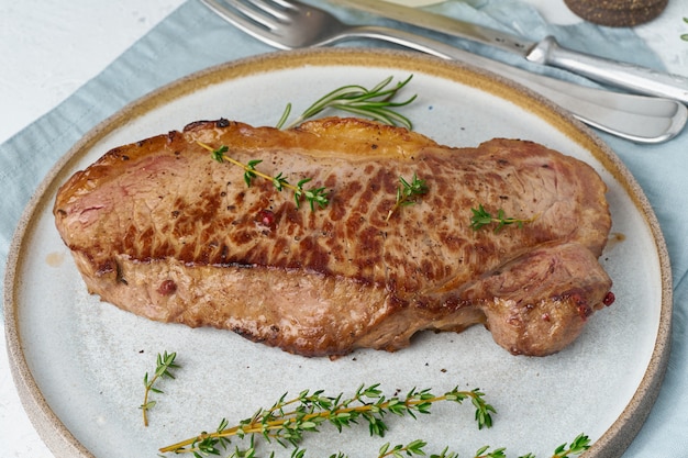 Foto bistecca di manzo chetogenica di dieta cheto, striploin sul piatto grigio su bianco. ricetta cibo paleo