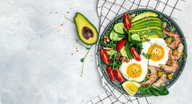 Ketogeen dieet ontbijt garnalen garnalen zacht gebakken ei verse salade tomaten komkommers en avocado op een lichte achtergrond Keto paleo lunch Bovenaanzicht