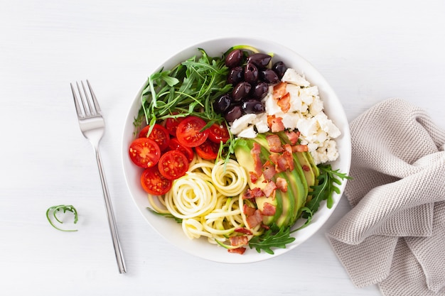 Ketogene lunchschaal. spiraalvormige courgette met avocado, tomaat, fetakaas, olijven, spek