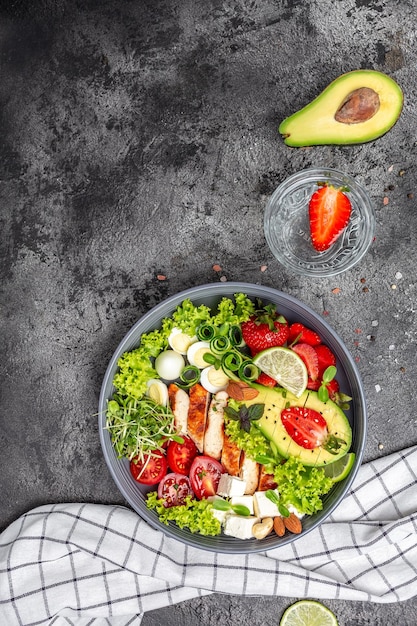 Ketogenic diet food, chicken fillet, quinoa, avocado, avocado, feta cheese, quail eggs, strawberries, nuts and lettuce. healthy meal concept, vertical image. top view place for text.