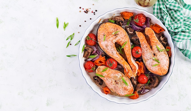 Ketogenic dinner. Baked salmon fish steak with tomatoes, mushrooms and red onions. Keto/paleo diet menu. Top view, overhead