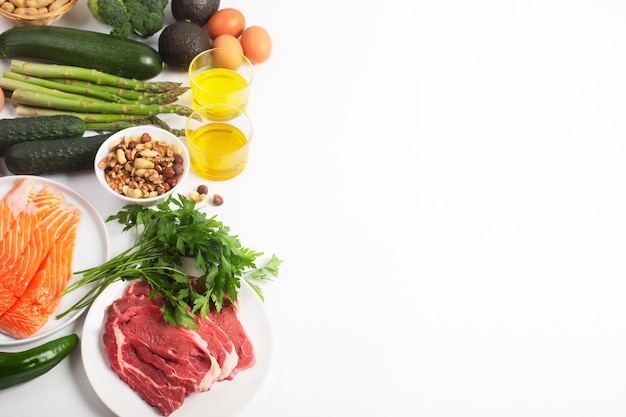 Ketogenic, keto diet, including vegetables, meat and fish, nuts and oil on white background with copy space