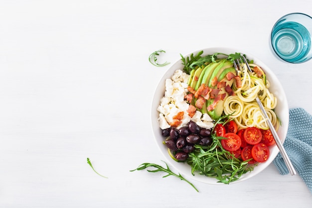 Foto ciotola da pranzo chetogenica: zucchine a spirale con avocado, pomodoro, formaggio feta, olive, pancetta